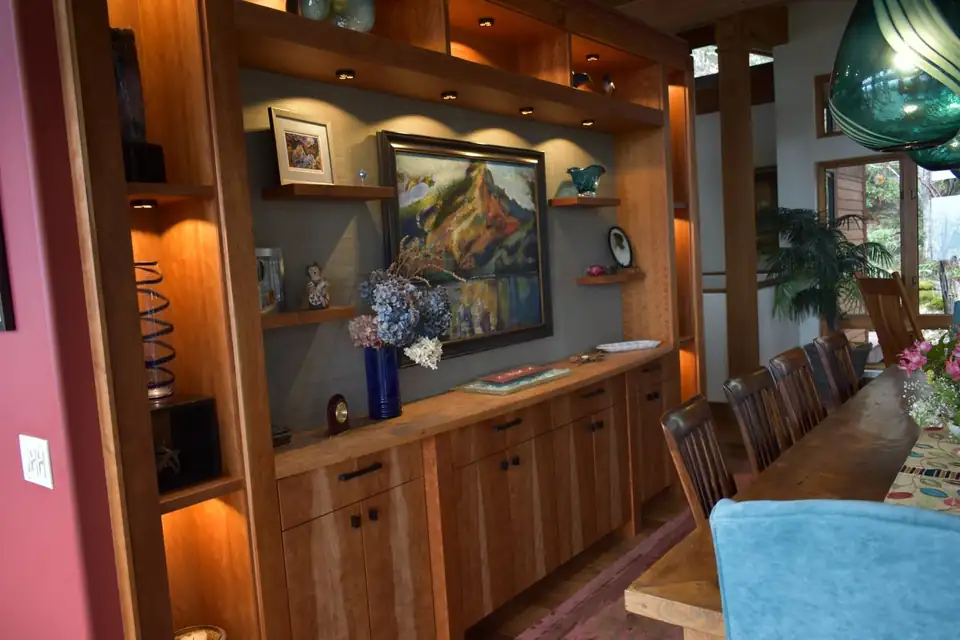 Custom cabinetry in Phoenix, OR by William Olsen Designs: wall-length cherry built-in with lit display shelves, a framed painting niche and lower cabinets