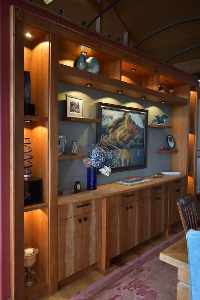 Cherry wall unit with glowing display shelves, a framed landscape painting niche and cabinet doors below