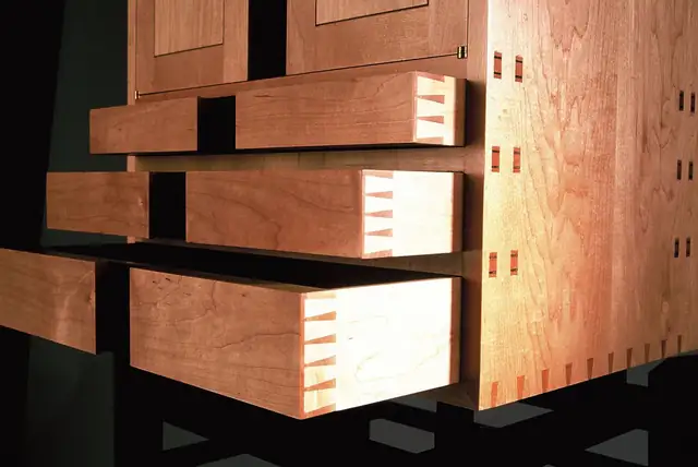 Cherry drawers with exposed dovetail joints set in a black frame