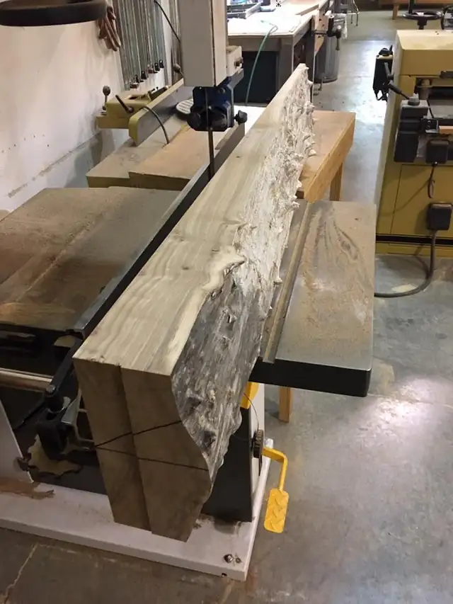 Live-edge hardwood slab on a jointer bed inside the woodworking shop